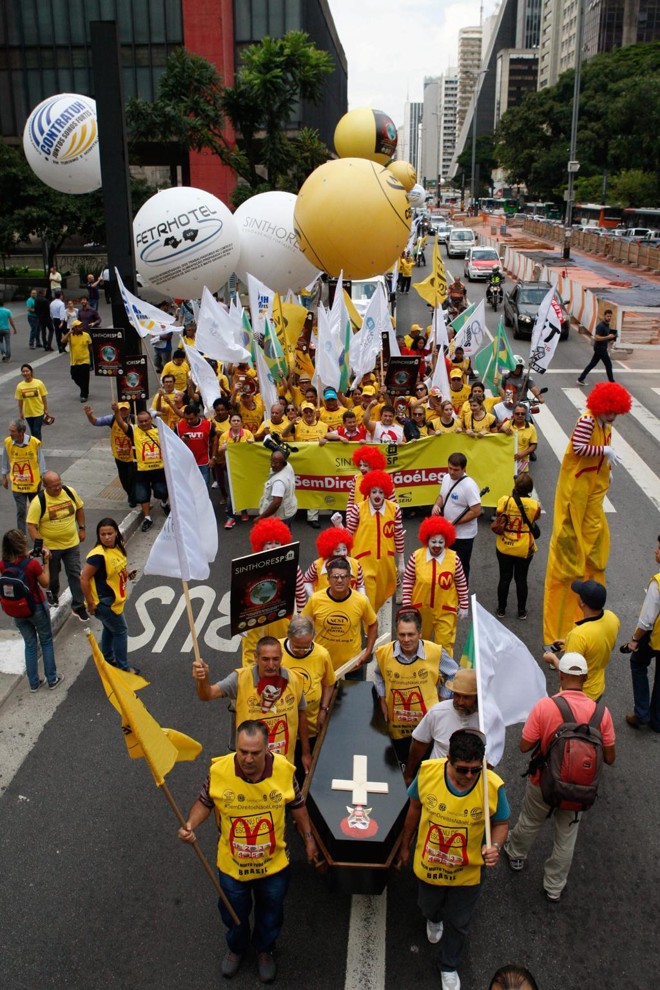 No saguão do Museu de Arte de São Paulo (MASP), cerca de 700 pessoas se reuniram com cartazes, muitas fantasiadas como o palhaço “Ronald McDonald”, e no final incendiaram um caixão simbolizando o enterro do personagem. | Carlos Villalba R./EFE