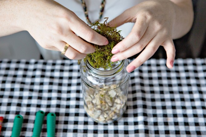 2. Camadas Comece a montar as camadas que farão a decoração do vaso. Primeiro, coloque pedrinhas e na sequência o musgo seco. Molhe-o em um recipiente com água e retire todo o líquido antes de colocá-lo no vaso. Use os hashis para espalhá-los |