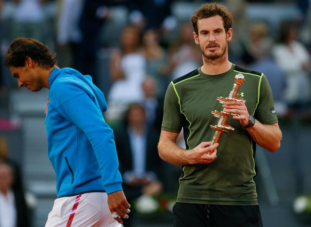 Andy Murray (à dir.) comemora com o troféu do Masters 1000 de Madri, conquistado sobre Rafael Nadal (ao fundo). | JuanJo Martin./EFE