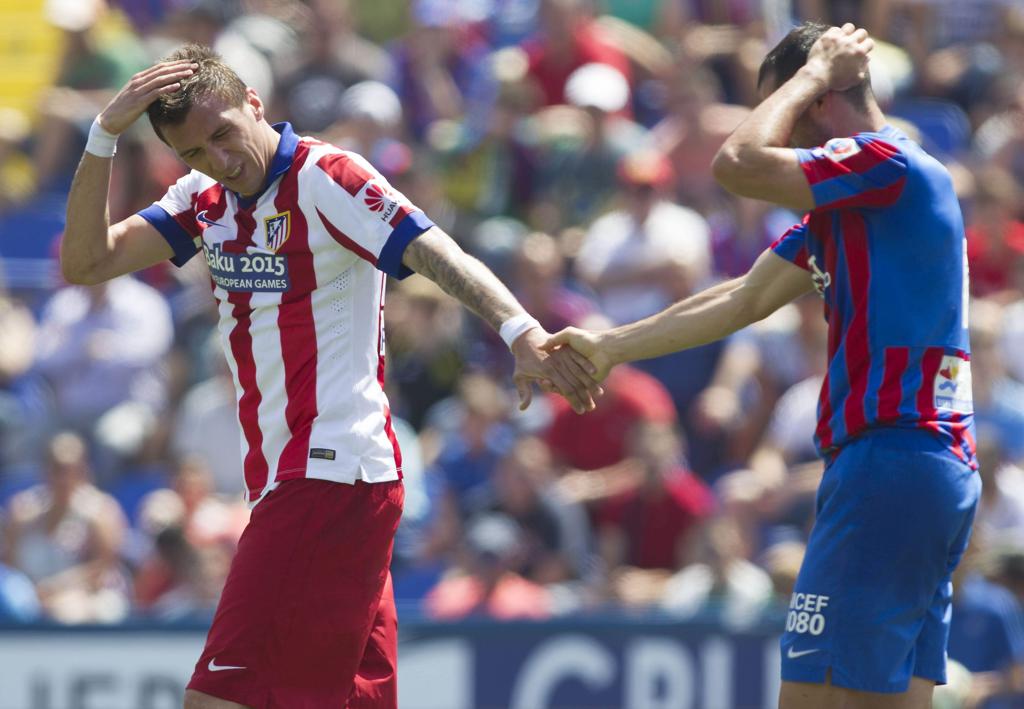 O atacante do Atlético de Madrid, Mario Mandzukic, cumprimenta Loukas Vintra, do Levante, após trombada de cabeça numa disputa de bola. | Miguel Ángel Polo/EFE