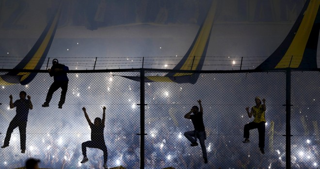 Torcedores do Boca pendurados na grade durante o clássico argentino. | MARCOS BRINDICCI/REUTERS