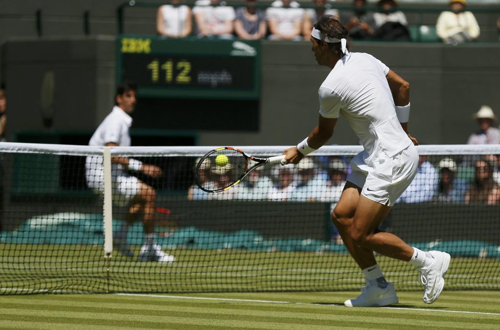 Belluci, ao fundo, acompanha a subida à rede de Rafael Nadal: eliminação na estreia. | STEFAN WERMUTH/REUTERS