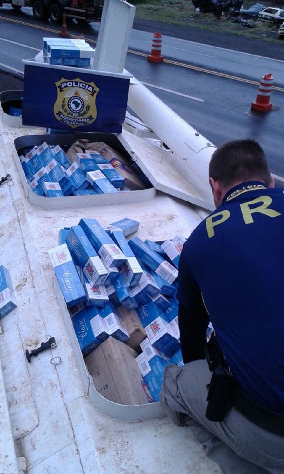 Caminhão-silo é flagrado com 215 mil maços de cigarro contrabandeados Policial rodoviário vistoria o caminhão, que transportava cigarros contrabandeados no lugar de ração | PRF/Divulgação