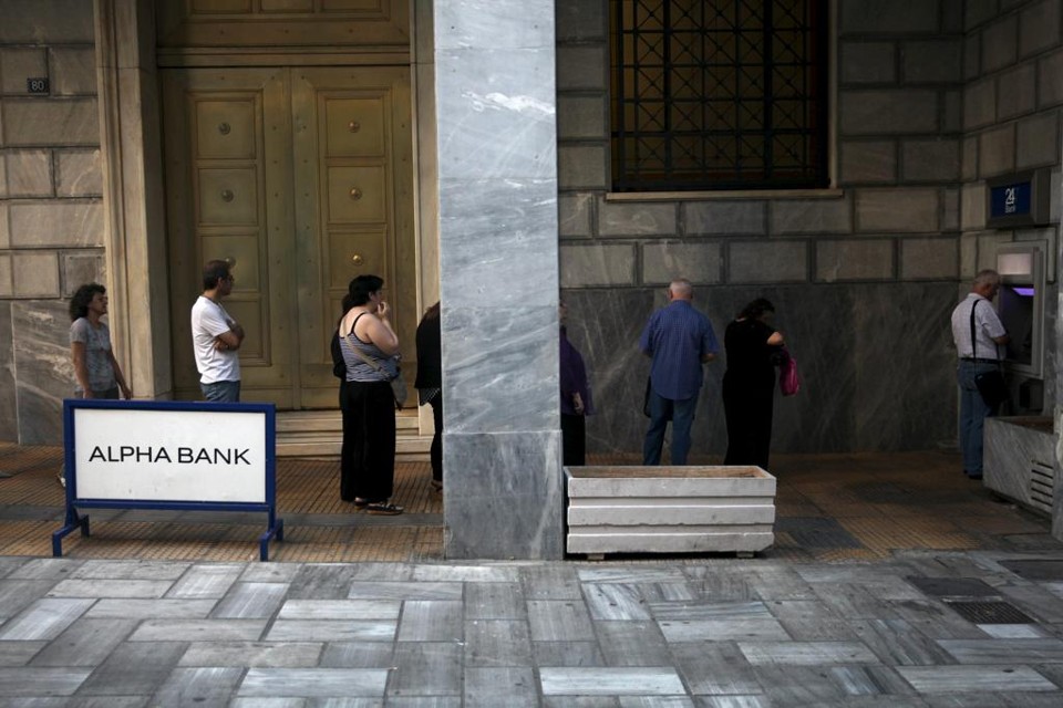 Gregos fazem fila para sacar em caixa eletrônico: pacote deve permitir normalização do sistema bancário. | YIANNIS KOURTOGLOU/REUTERS
