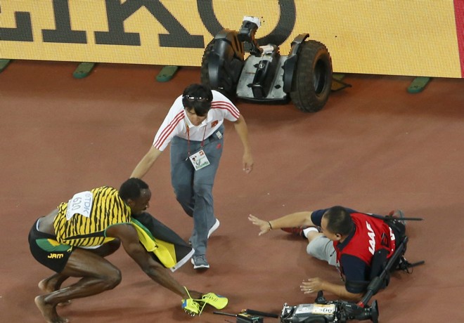 Cinegrafista pede desculpas a Bolt depois de levá-lo ao chão. A resposta é um sorriso amarelo. No fim, era tudo festa para o jamaicano. | KIM KYUNG-HOON/REUTERS