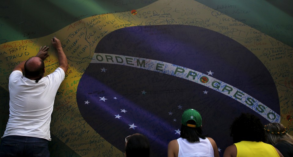 Brasileiros assinam a bandeira do Brasil: governo pede mais otimismo. | Nacho Doce/Reuters