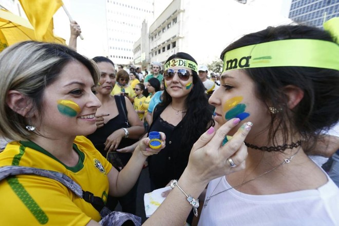 Manifestantes se pintam de verde e amarelo antes de acompanhar o protesto até a Boca Maldita, em Curitiba. | Albari Rosa/Gazeta do Povo