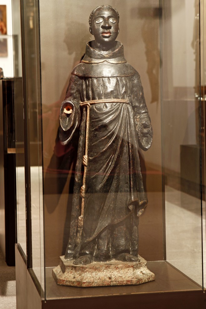 BISPO SÃO GRATO - O santo de origem grega, acalmador das tempestades e protetor das lavouras, teria sido feito, segundo Ângela, por imigrantes italianos da região do Mossunguê. É possível ver alguns símbolos que rementem à origem italiana, como as folhas de vinhas, por exemplo. A imagem (assim como algumas outras esculturas do Masac) está incompleta: ele carrega uma bandeja vazia, que deveria trazer a cabeça de São João Batista (ele teria encontrado a cabeça do santo degolado). | Antônio More/Gazeta do Povo