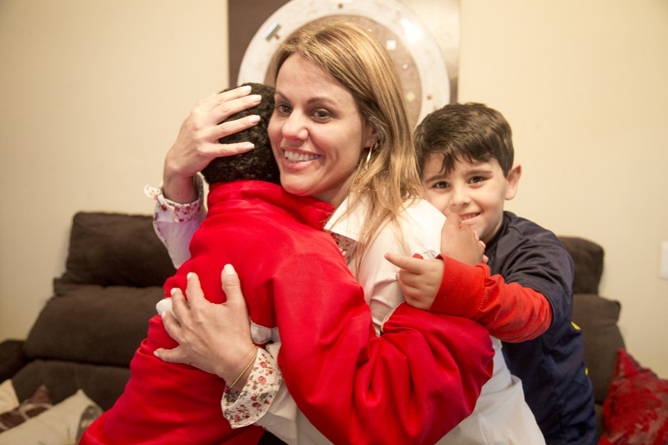 Pedro vê a mãe, a servidora do TJ-PR Marina Santos, abraçar o apadrinhado Lucas*, de 12 anos. Ela optou por não saber o que tinha levado o menino ao abrigo, até o dia que ele contou. | Fotos: Hugo Harada/Gazeta do Povo