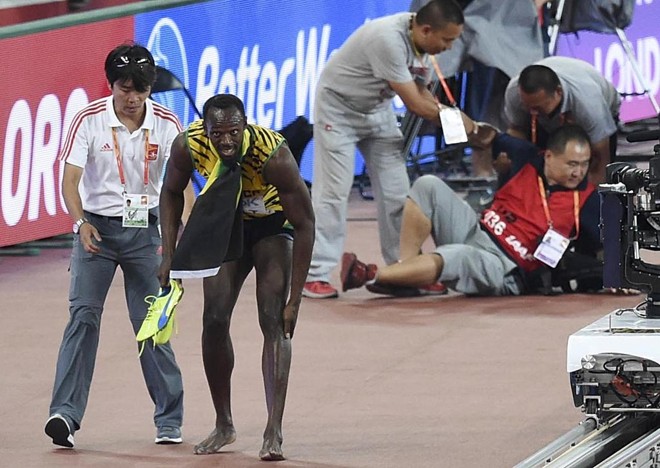 Mancando um pouco, Bolt deixa para trás o acidente e continua a curtir mais uma conquista mundial. Enquanto isso, o cinegrafista, pra lá de envergonhado, é auxiliado por companheiros. | CHINA STRINGER NETWORK/REUTERS