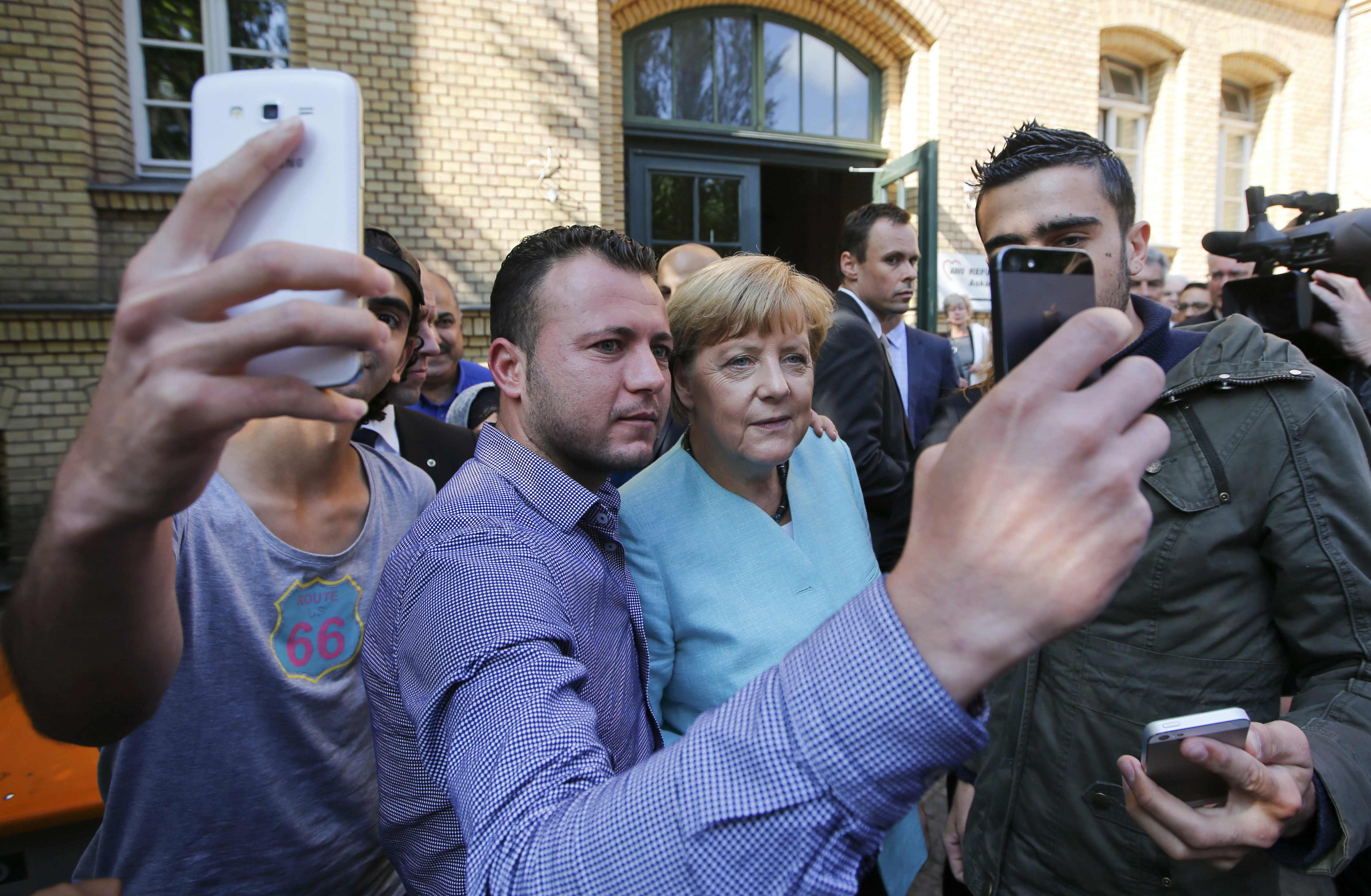 Migrantes na selfie com Merkel. | Fabrizio Bensch/Reuters