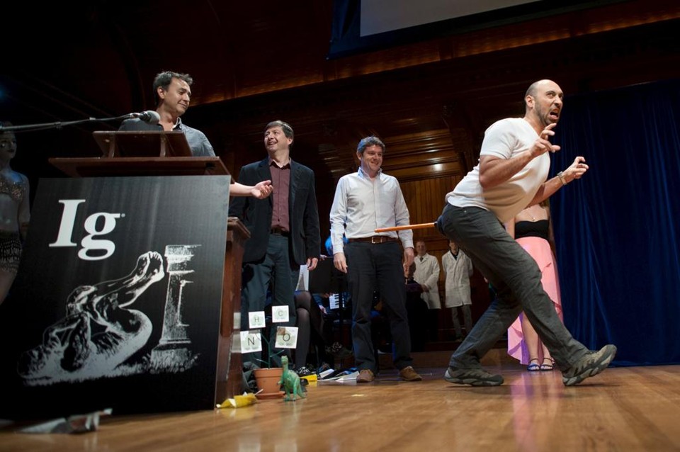 Bruno Grossi demonstra o experimento de sua equipe ao receber o Ig Nobel de Biologia. Ele e seus colegas receberam o prêmio por um estudo que demonstrava que, ao colocar um peso na traseira de uma galinha, a ave anda de uma maneira similar ao que se pensa que os dinossauros andavam | Gretchen Ertl/REUTERS