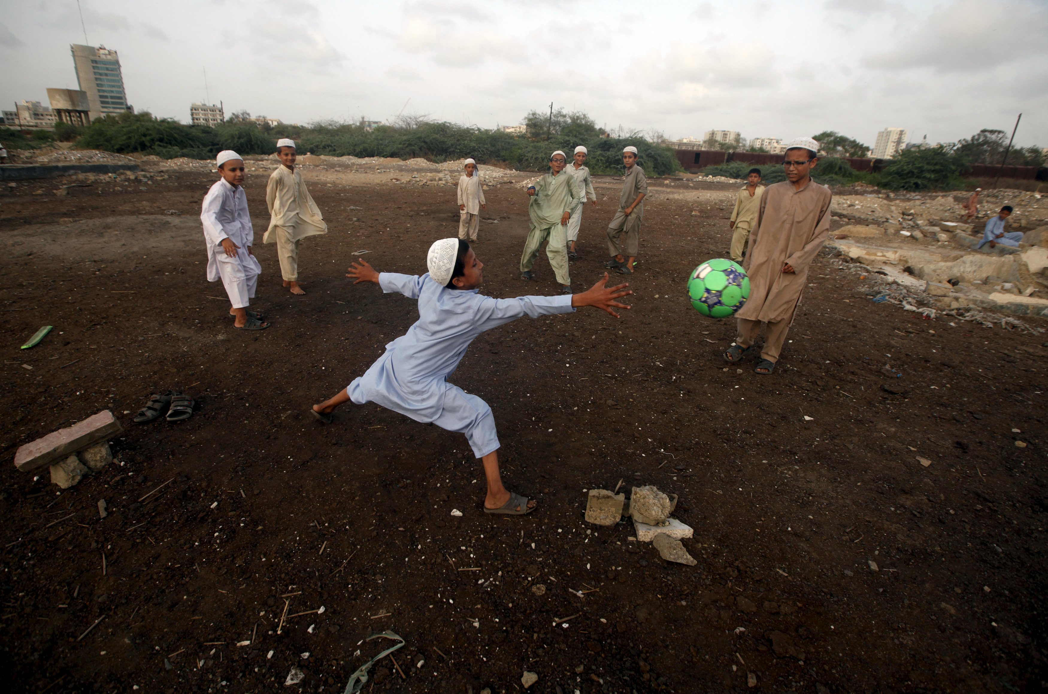 Crianças jogando futebol em uma favela;﻿A Karachi United Football Foundation acredita que o futebol possa trazer diversidade étnica, sectária e sexual ao esporte paquistanês | Athar Hussain/Reuters