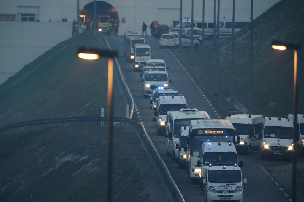 Veículos da polícia francesa transportam imigrantes que invadiram a linha férrea do Eurotúnel. | Pascal Rossignol/Reuters