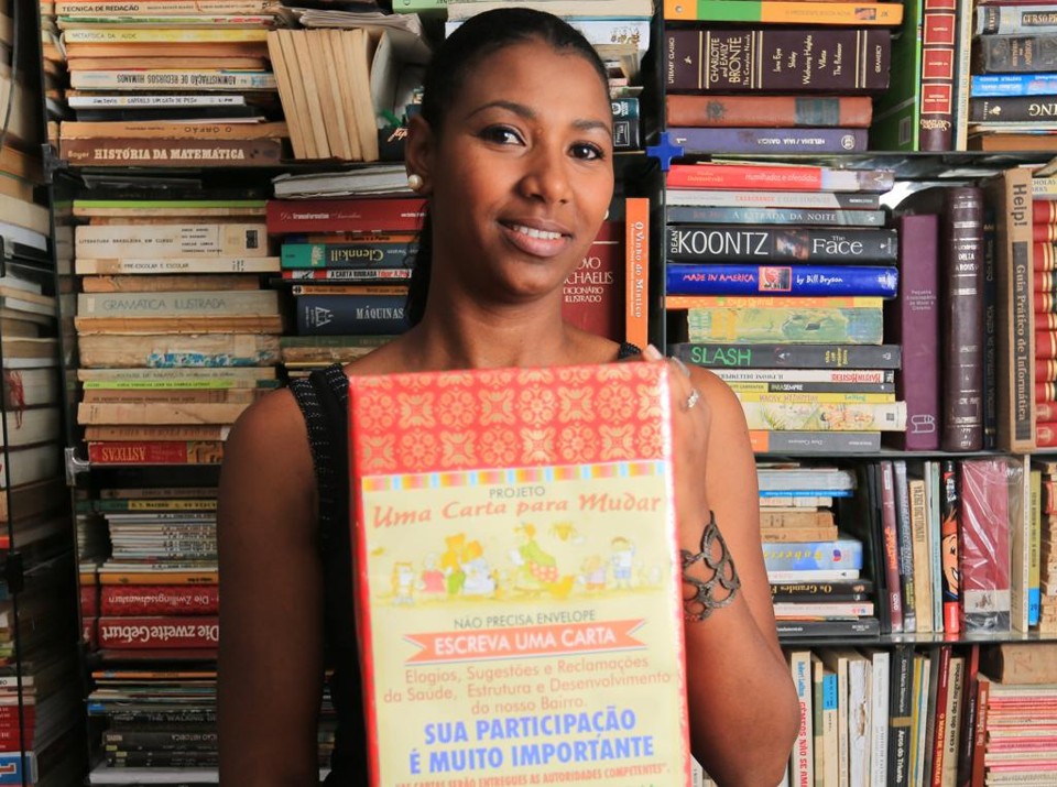 Luciana Cortes, a biblioteca caseira que divide com o marido Fernando e uma das famosas caixas que atiçaram a participação popular no Rio Bonito. | Ivonaldo Alexandre / Gazeta do Povo