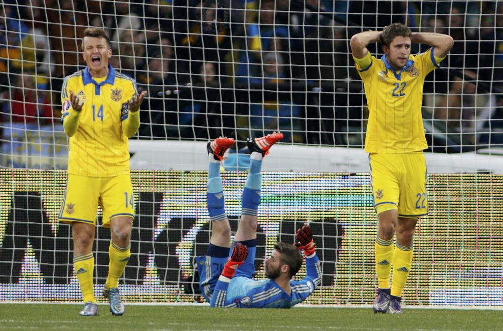 O goleiro De Gea se recupera de uma das muitas defesas que fez na partida contra a Ucrânia, enquanto os adversários lamentam a derrota. | Valentyn Ogirenko/Reuters