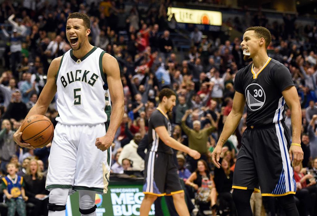 Carter-Williams comemora a vitória do Milwaukee Bucks ao lado de um desolado Stephen Curry. | Benny Sieu/USA Today Sports