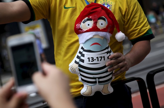 Em São Paulo, manifestante vestido com a camisa a camisa da seleção brasileira de futebol segura um Pixuleco fantasiado de Papai Noel. | Nacho Doce/Reuters