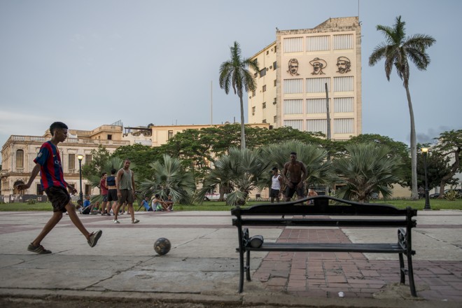 Vestido com camiseta do Barcelona garoto joga bola em uma praça no centro de Havana. | Henry Milléo