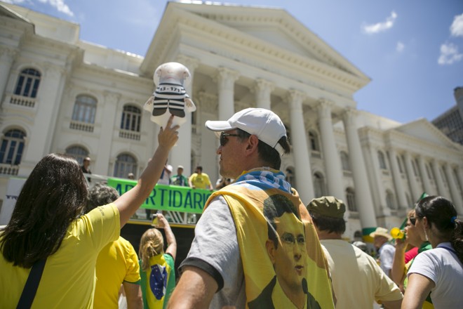 Manifestantes na Santos Andrade. Uma segura um boneco Pixuleco, outro usa uma bandeira com o rosto do juiz federal Sérgio Moro. | Marcelo Andrade/Gazeta do Povo