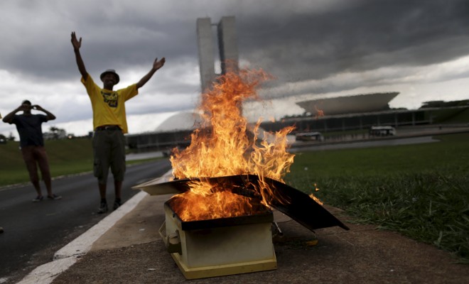 Manifestantes, em Brasília, ateiam fogo ao caixão que continha a imagem da presiente Dilma e uma bandeira do PT. | Ueslei Maarcelino /Reuters