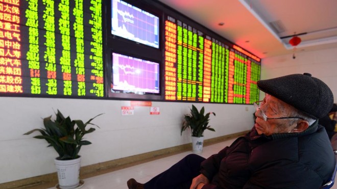 Investidor olha placar da bolsa chinesa. | STR/AFP