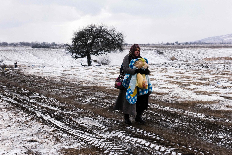 Refugiada cruza, carregando um bebê, um campo na Sérvia. | Dimitar Dilkoff/AFP