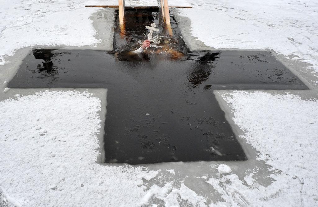 Padre ortodoxo mergulha nas gélidas águas de Moscou em pleno inverno russo durante a Festa da Epifania | OLGA MALTSEVA/AFP