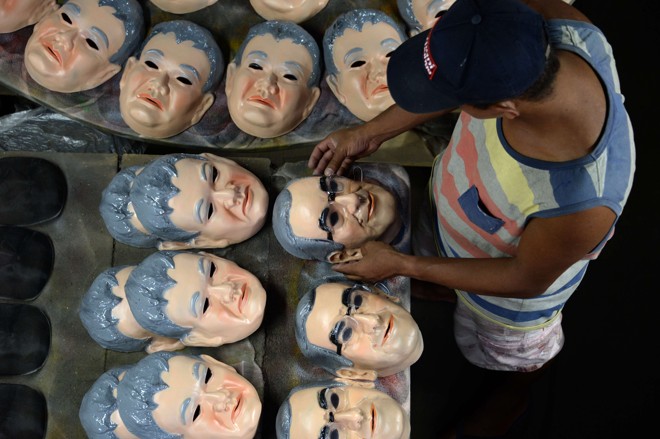 Rapaz deixa em ordem as máscaras de Eduardo Cunha. | VANDERLEI ALMEIDA/AFP