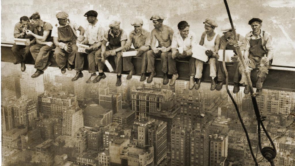 “Men at Lunch”, a fotografia, mostra um grupo de operários sentados numa viga a 60 andares de altura. Mais tarde se descobriu que a imagem foi posada. | Reprodução