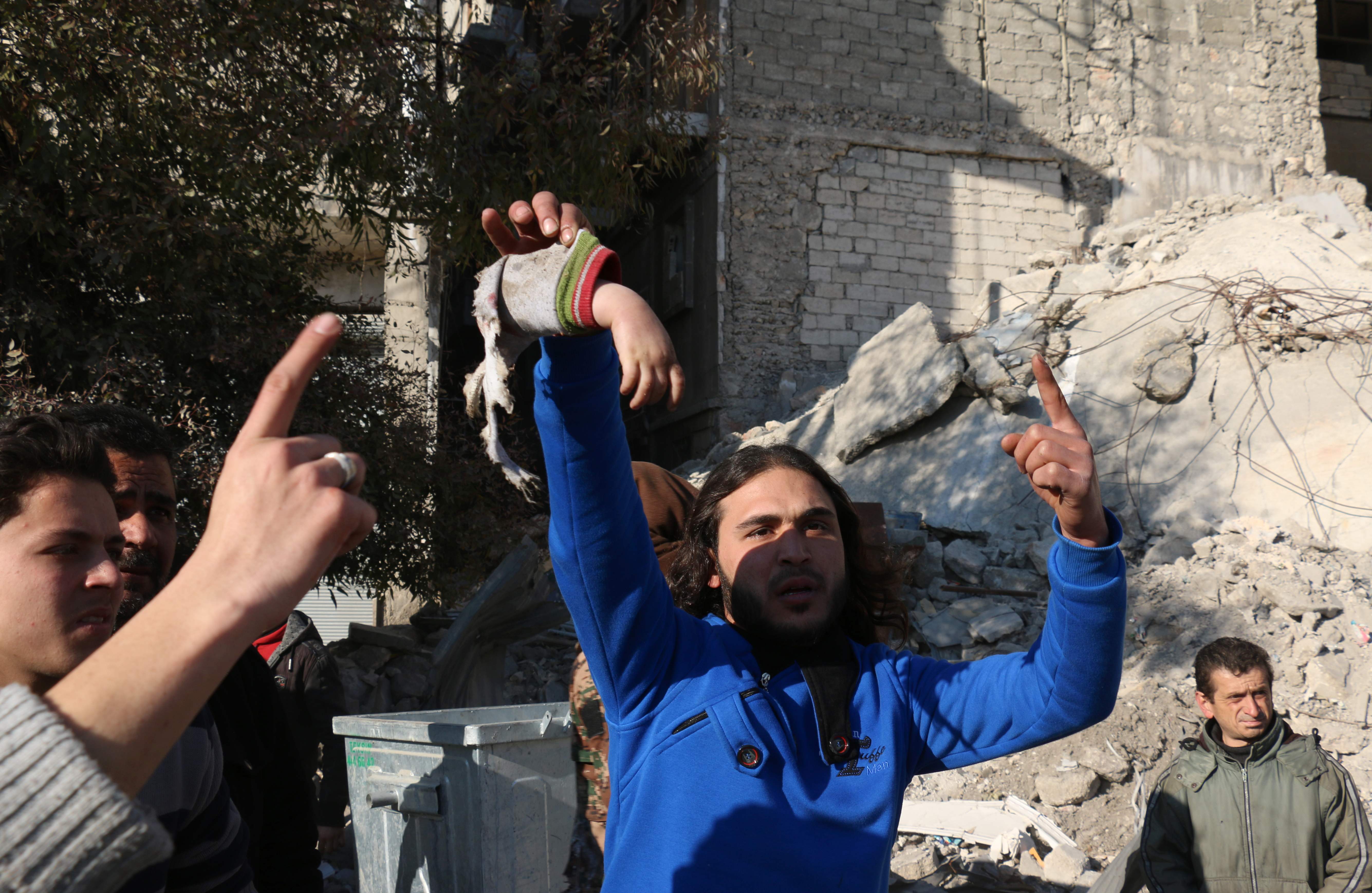 Homem sírio segura uma mão de criança supostamente após ataques aéreas na cidade de Aleppo | AMEER AL-HALBI/AFP