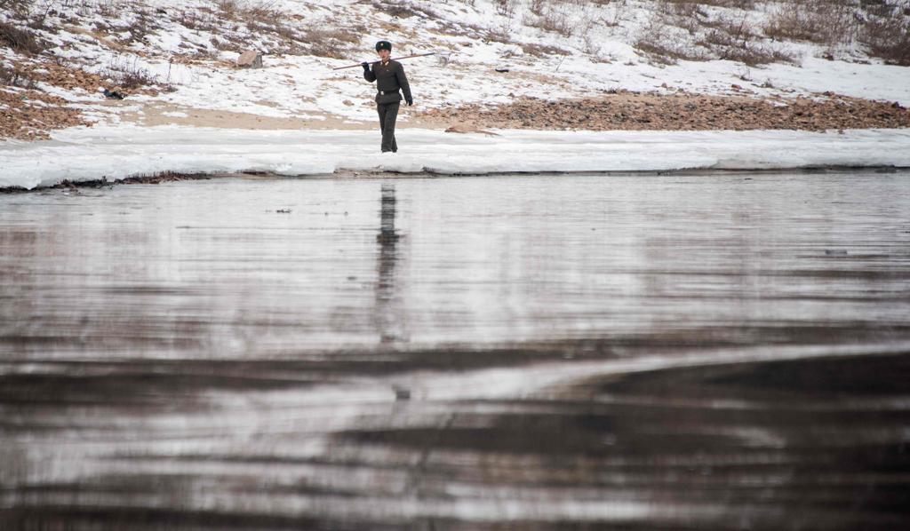 Um soldado norte-coreano caminha ao longo das margens do rio Yalu na cidade norte-coreana de Sinuiju | JOHANNES EISELE/AFP