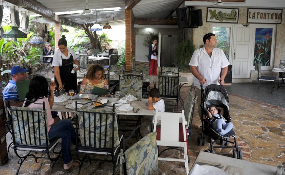 Família de Eddy Relova, de 23 anos, se reúne para almoçar em um “paladar” de Havana: cordão de ouro no pescoço. | Yamil Lage/AFP