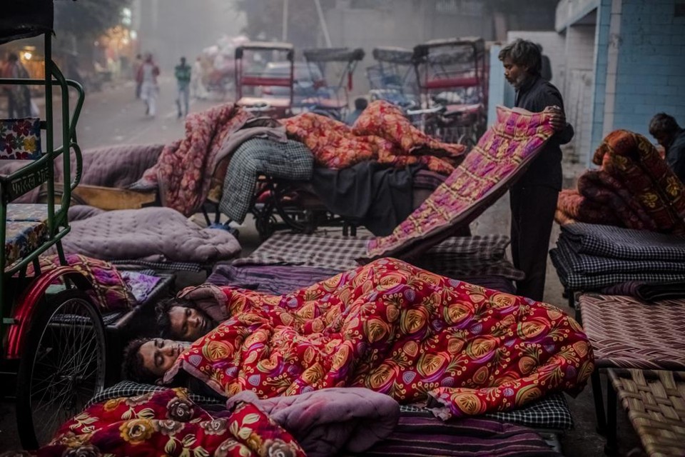 Homens dividem cobertor alugado por um mercador na cidade de Délhi, na Índia | DANIEL BEREHULAK/NYT