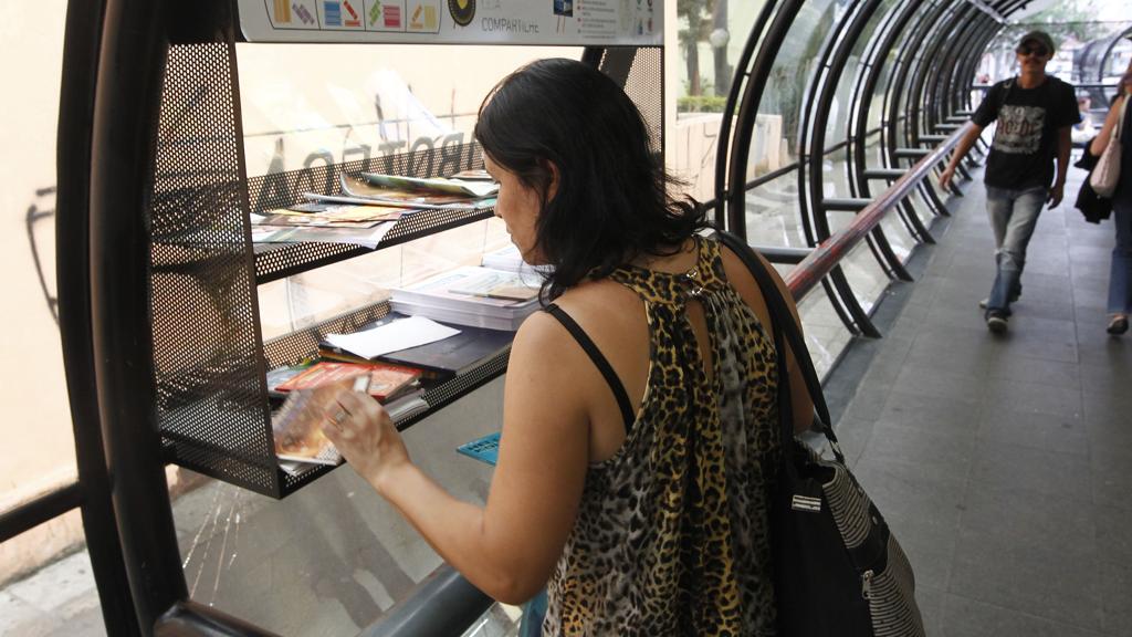 Mulher observa os livros disponíveis numa das Tubotecas. | Pedro Serapio/Gazeta do Povo