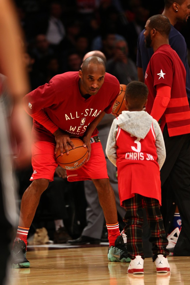 Kobe Bryant brinca com criança no All-Star Game. | ELSA/AFP