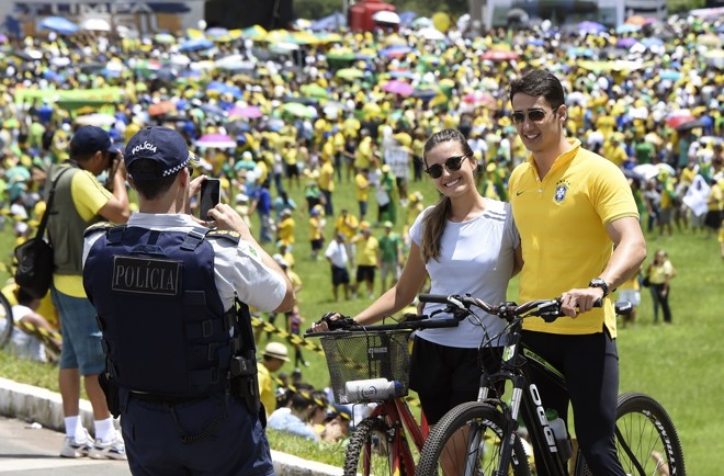 Casal pede ajuda de policial para registrar a participação no protesto em Brasília. | EVARISTO SA/AFP