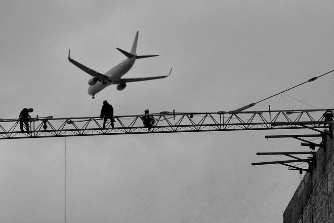 Operários trabalham na construção de um prédio na Av. Visconde de Guarapuava, no centro de Curitiba e o avião passando ao fundo - Foto: Henry Milleo / Gazeta do Povo | 