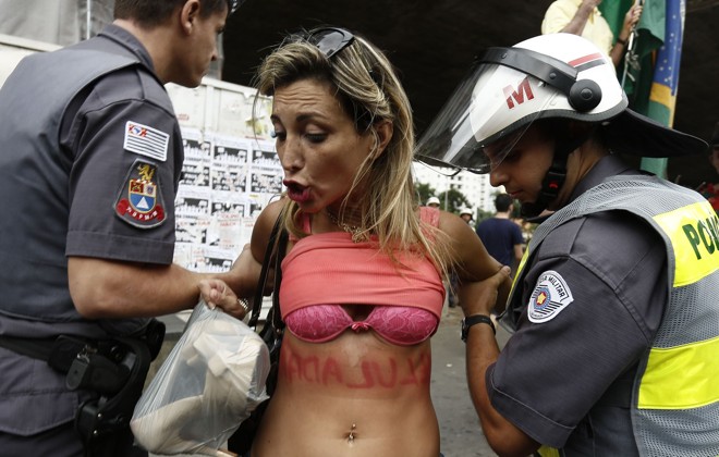 Manifestante é levada pela polícia paulistana após levantar a blusa durante protesto na Avenida Paulista | Miguel Schincariol/AFP