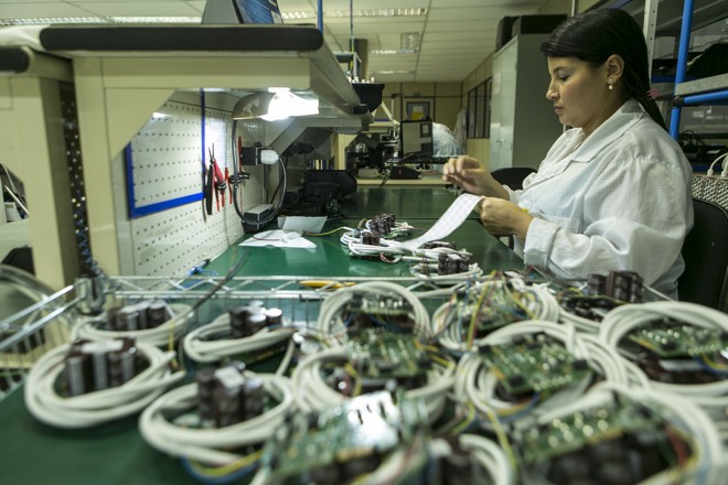 Os funcionários da linha de produção instalam, nas placas, itens mais pesados – como os capacitores, que armazenam energia para o disparo do flash da câmera. | (foto: Marcelo Andrade/Gazeta do Povo)