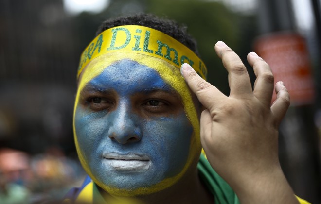 Participante na Avenida Paulista pinta o rosto com as cores da bandeira brasileira | Miguel Schincariol/AFP