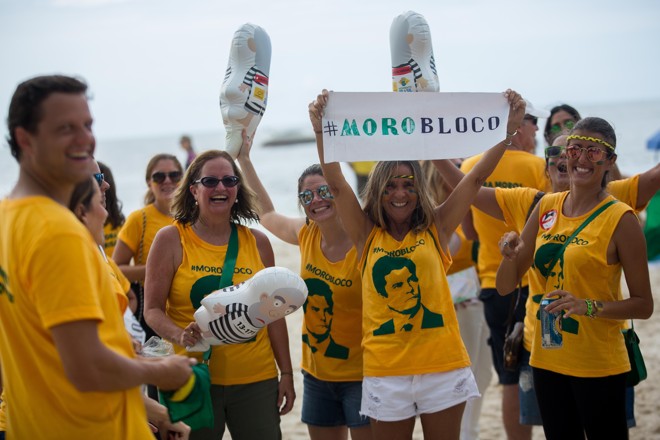 Na praia de Copacabana, grupo usa camisetas com a hashtag #morobloco e segura miniaturas do boneco pixuleco. Foto: | Mauro Pimentel/Folhapress