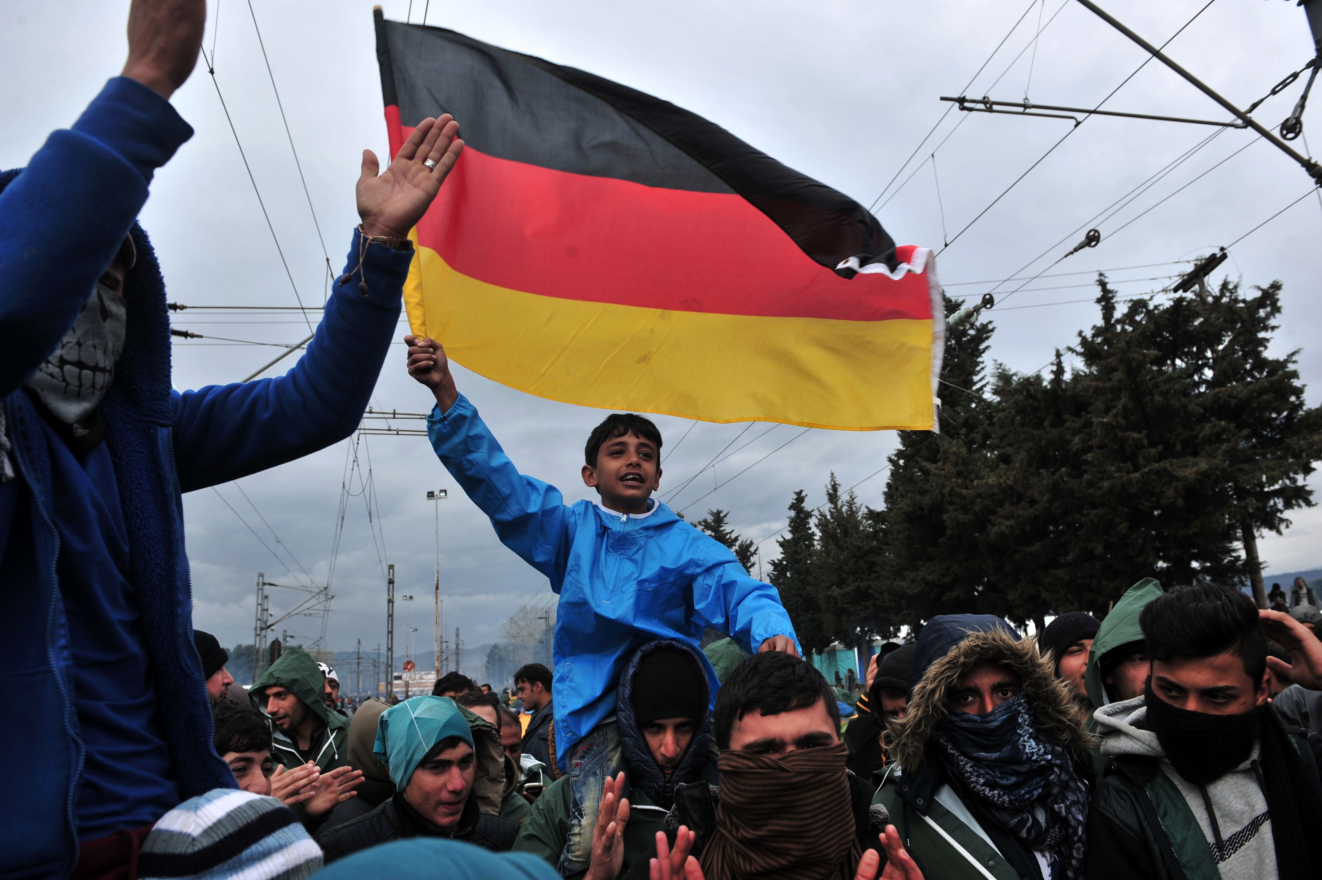 Jovem imigrante segura bandeira alemã na fronteira da Grécia e Macedônia | SAKIS MITROLIDIS/AFP