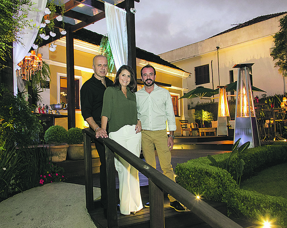 O casal Katiana Giarola e Paulo Castor (à esq.) e o chef Giuliano Hahn, sócios do restaurante Armazém Santo Antonio, receberam convidados na segunda-feira para o coquetel em comemoração aos 145 anos da casa onde está instalado, no São Francisco. | Naideron Jr.