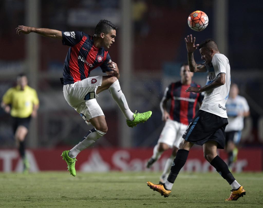 Emmanuel Mas, do San Lorenzo, disputa a bola com Luan, do Grêmio, no empate por 1 a 1 na Argentina. | Juan Mabromata/AFP