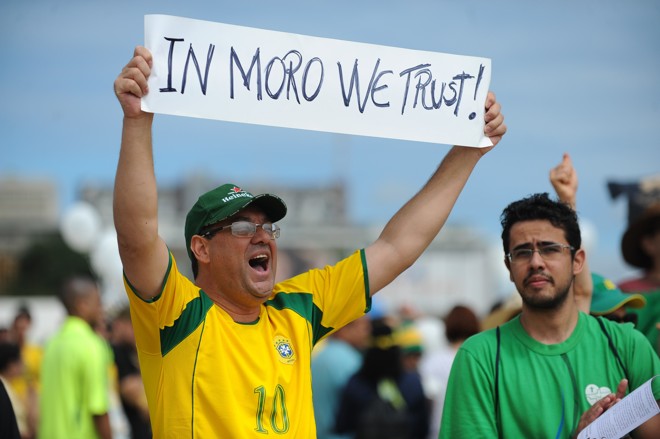 Em Brasília, participante de protesto exibe cartaz com a inscrição “In Moro we trust” (em Moro nós confiamos), fazendo alusão à frase “In God we trust” (em Deus nós confiamos), lema nacional dos Estados Unidos . Foto: | Andressa Anholete/AFP