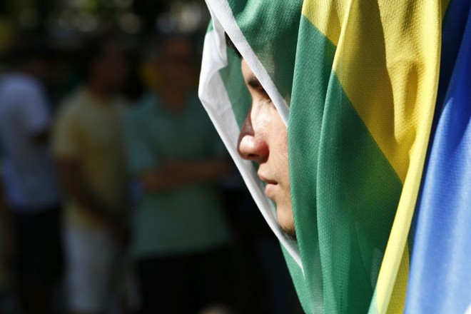 Manifestante acompanha votação com rosto coberto pela bandeira do Brasil na Praça Santos Andrade | Marcelo Andrade/Gazeta do Povo
