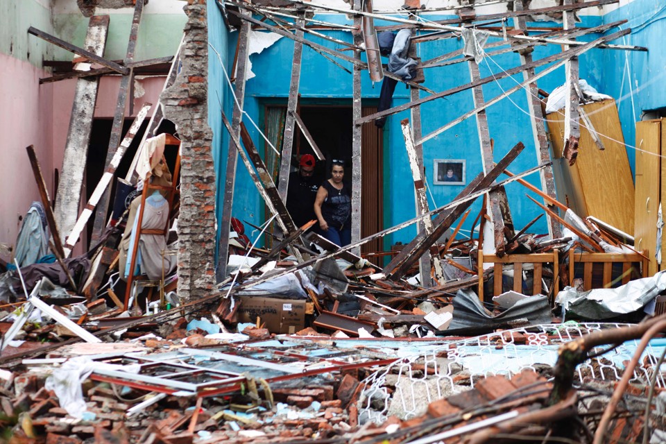 Moradora olha para os restos de sua casa atingida por um tornado em Dolores, no Uruguai | NICOLAS GARCIA/AFP