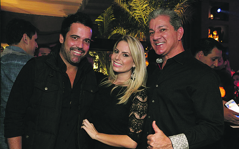 Iiiiiiiiiiiiiit’s Tiiiiiiiiiiiime!!! Bruce Buffer (à dir.), o mundialmente famoso locutor das lutas do UFC, mal chegou à cidade e foi conhecer a noite curitibana na quinta-feira. Ele esteve no Taj Bar, onde foi recebido por Evelyn Rebello, gerente comercial do grupo. Com eles na foto, o empresário Marcelo Fayt. | Kauana Bechtloff