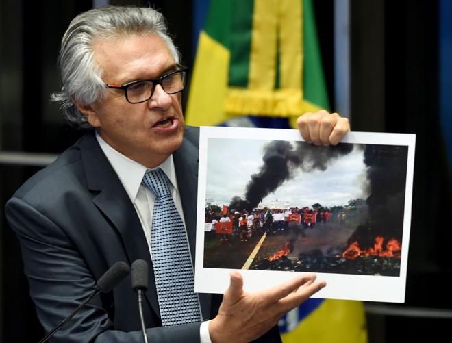 O senador Ronaldo Caiado mostra imagem de movimento social protestando em uma estrada. Organizações como o MST e a CUT são contra o impeachment de Dilma. | Evaristo Sá/AFP